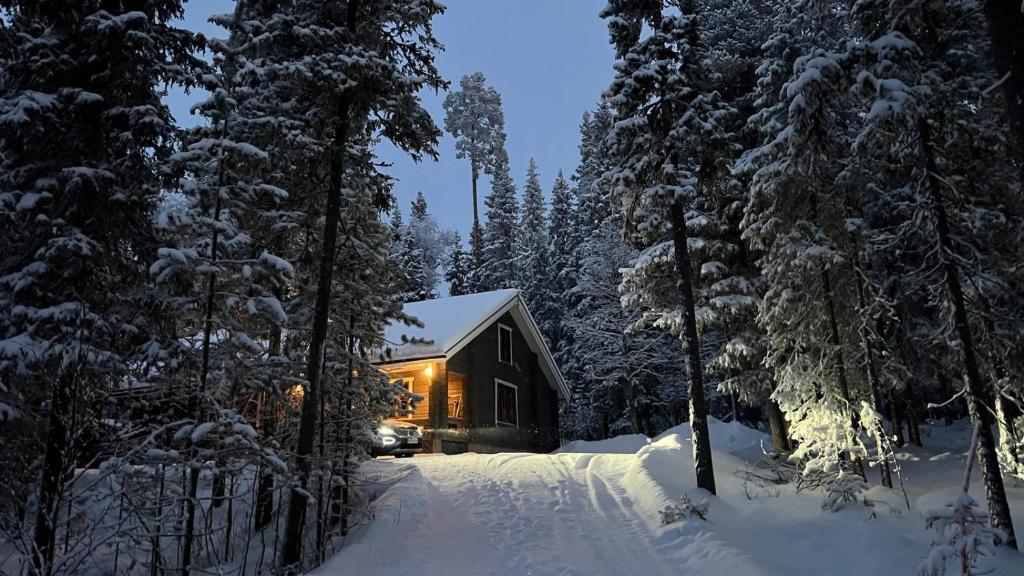 a house covered in snow in the woods at Rukan Karhumökki in Ruka