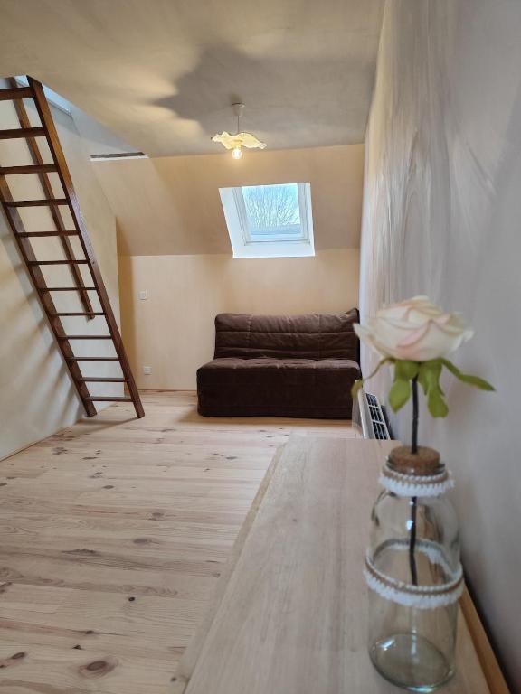 - un salon avec un canapé et une fleur dans un vase dans l'établissement Studio avec mezzanine, à Mamers