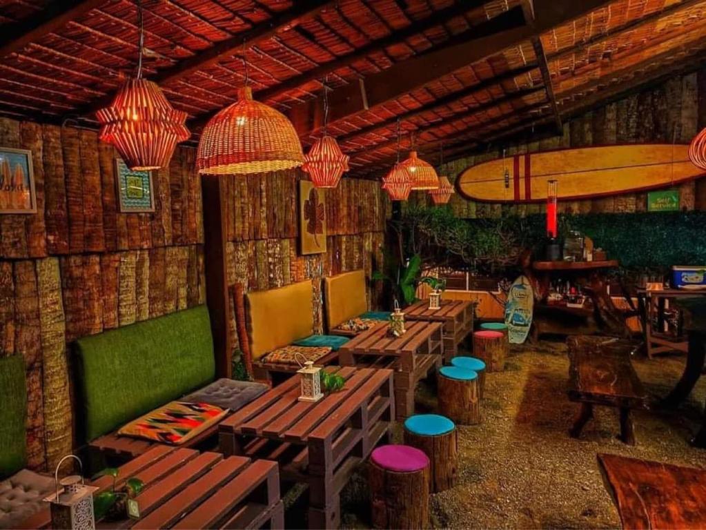 a restaurant with wooden tables and chairs and a surfboard at Nnyl Baler Surf & Stay in Zabali