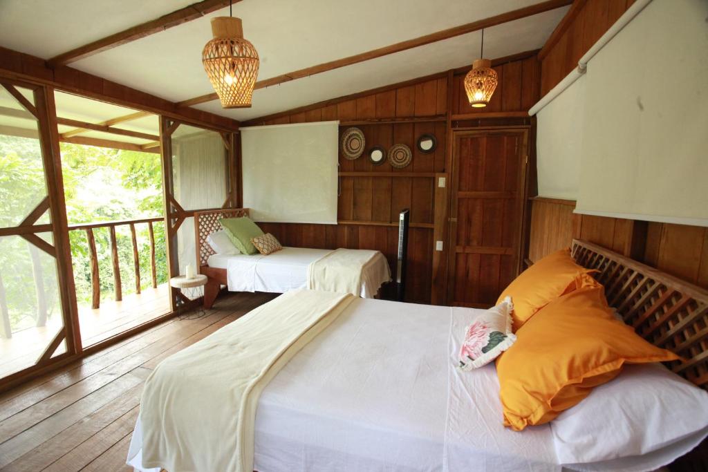 a bedroom with two beds and a balcony at Ave Sol River Sanctuary in Siquirres