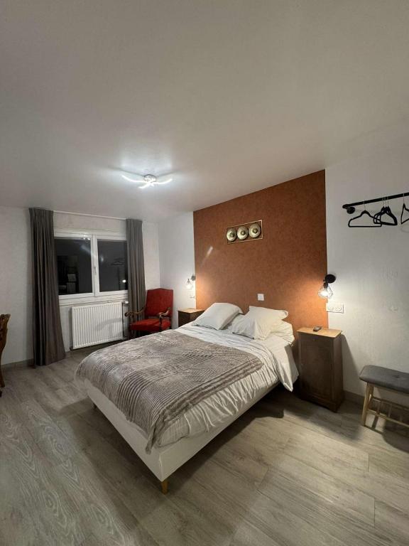 une chambre avec un grand lit et une chaise rouge dans l'établissement Le Napoléon, à Corps