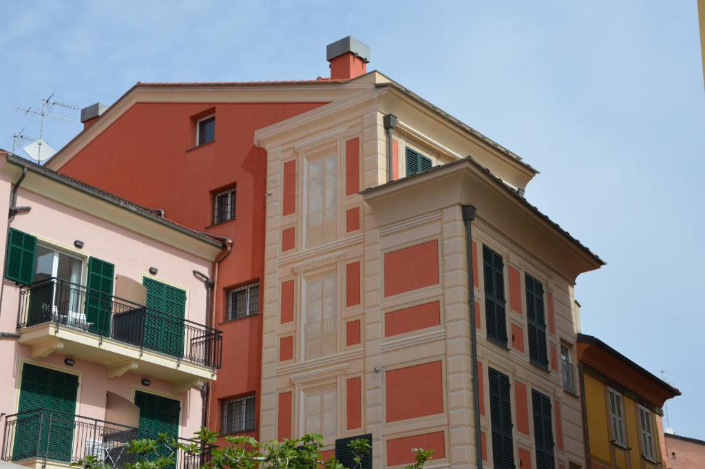 a red building with green shutters on it at San Matteo Apartments in Loano