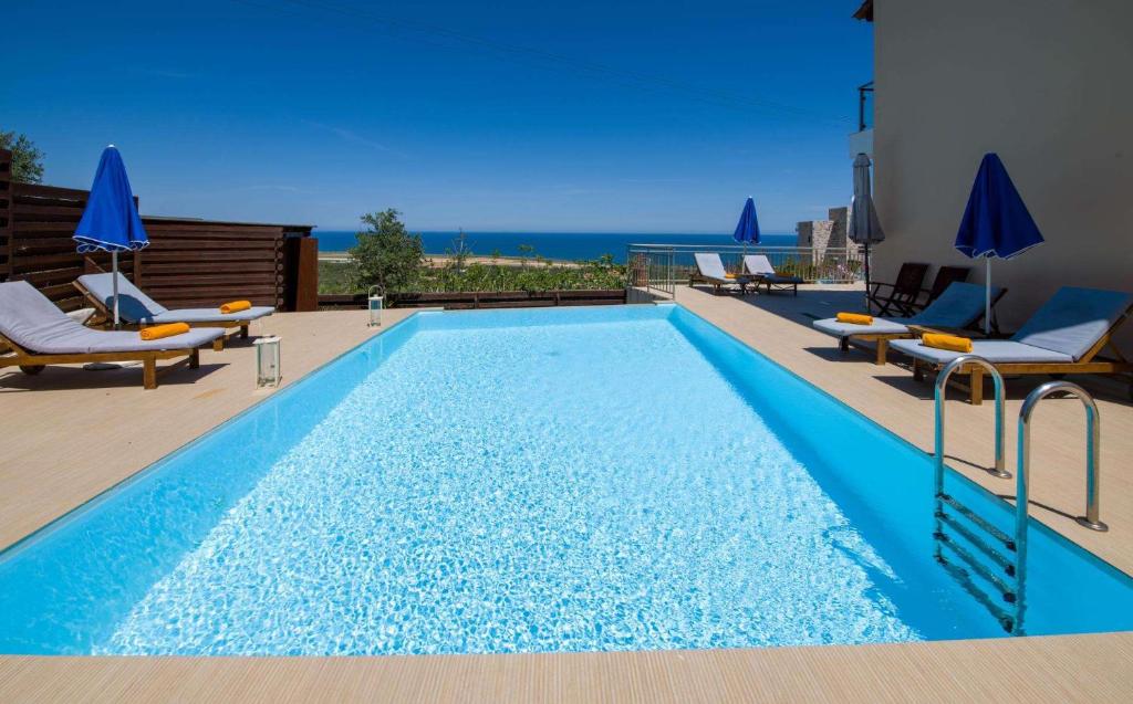 a swimming pool with chairs and the ocean in the background at Marilia by Vintage Travel in Maleme