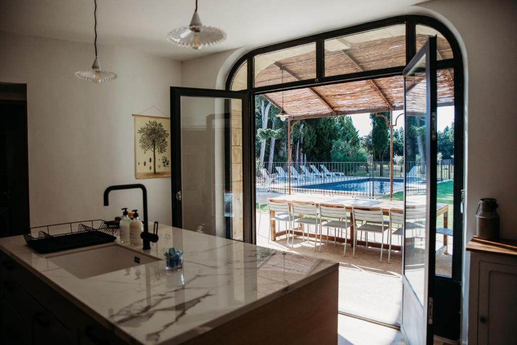 d'une cuisine avec une porte en verre offrant une vue sur la piscine. dans l'établissement Mas des Ecoliers - Ecochic family farmhouse, à Châteaurenard