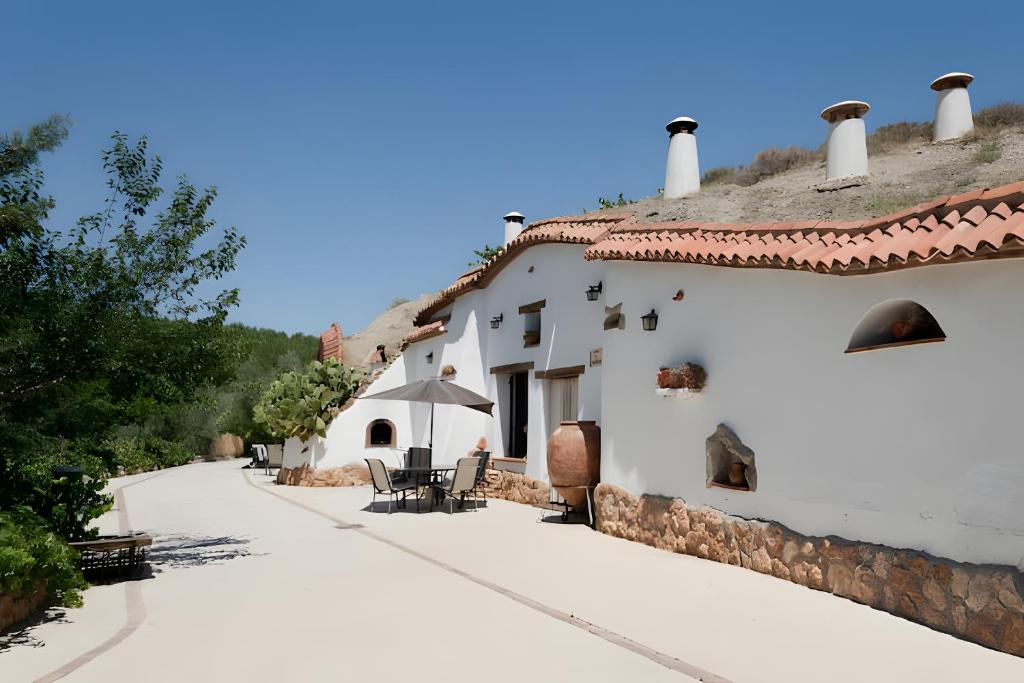 a white building with a table and an umbrella at La Chumbera in Benalúa de Guadix