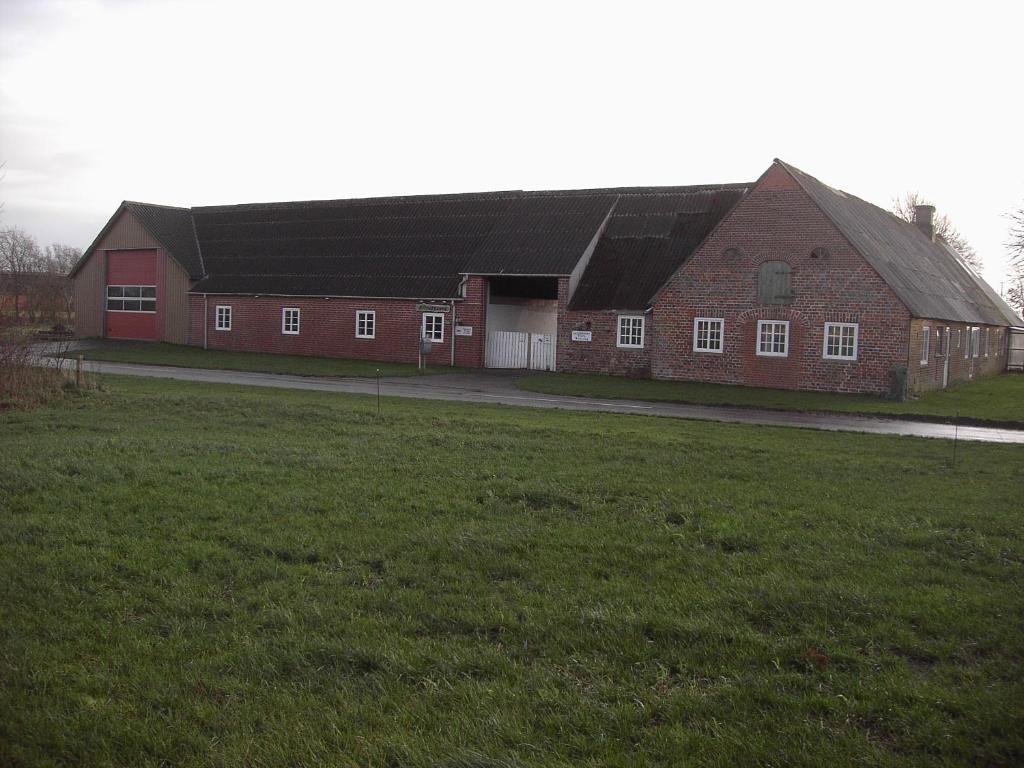 un gran edificio de ladrillo rojo con un campo delante en Astrupgaard Farm Holiday, en Skærbæk