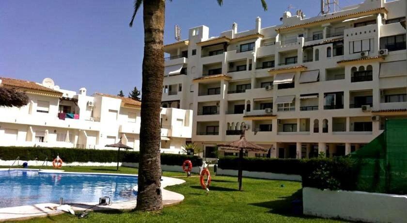 duży apartamentowiec z basenem i palmą w obiekcie 3-401-Apartamento 1 dormitorio w mieście El Puerto de Santa María