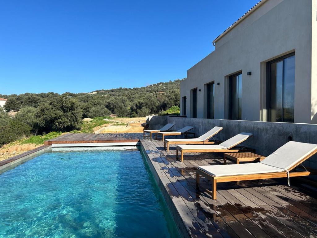 une piscine avec des chaises longues sur un immeuble dans l'établissement Villa Giuliana Paisible & spacieuse AREGNO, à Aregno