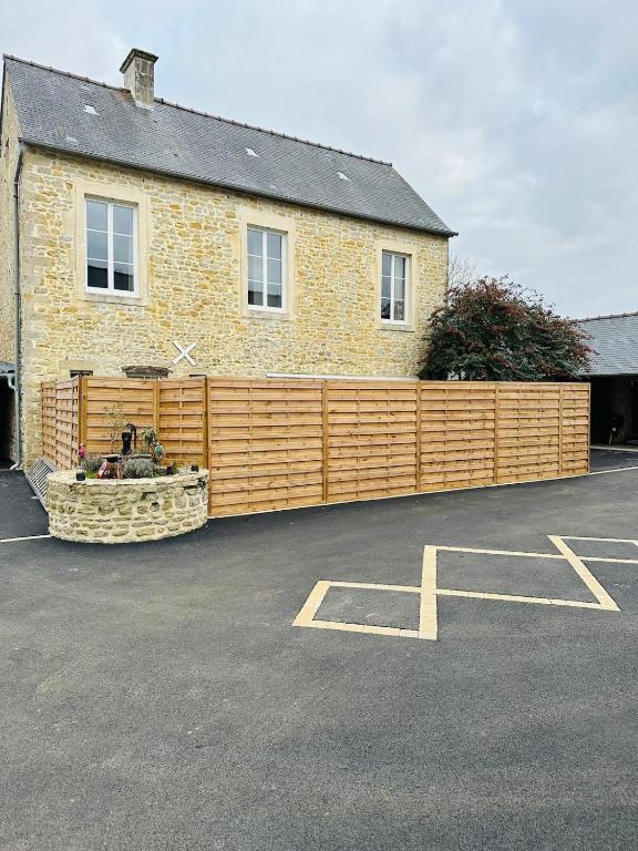 un bâtiment avec une clôture en bois dans un parking dans l'établissement L'hortensia, à Juaye-Mondaye