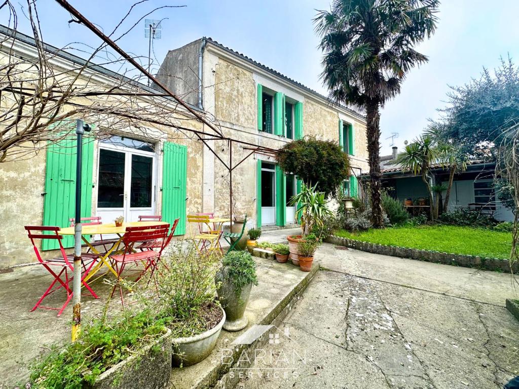 une maison avec des volets verts et une table dans une cour dans l'établissement Charmante Maison Familiale - Grande Capacité, à Saint-Laurent-de-la-Prée