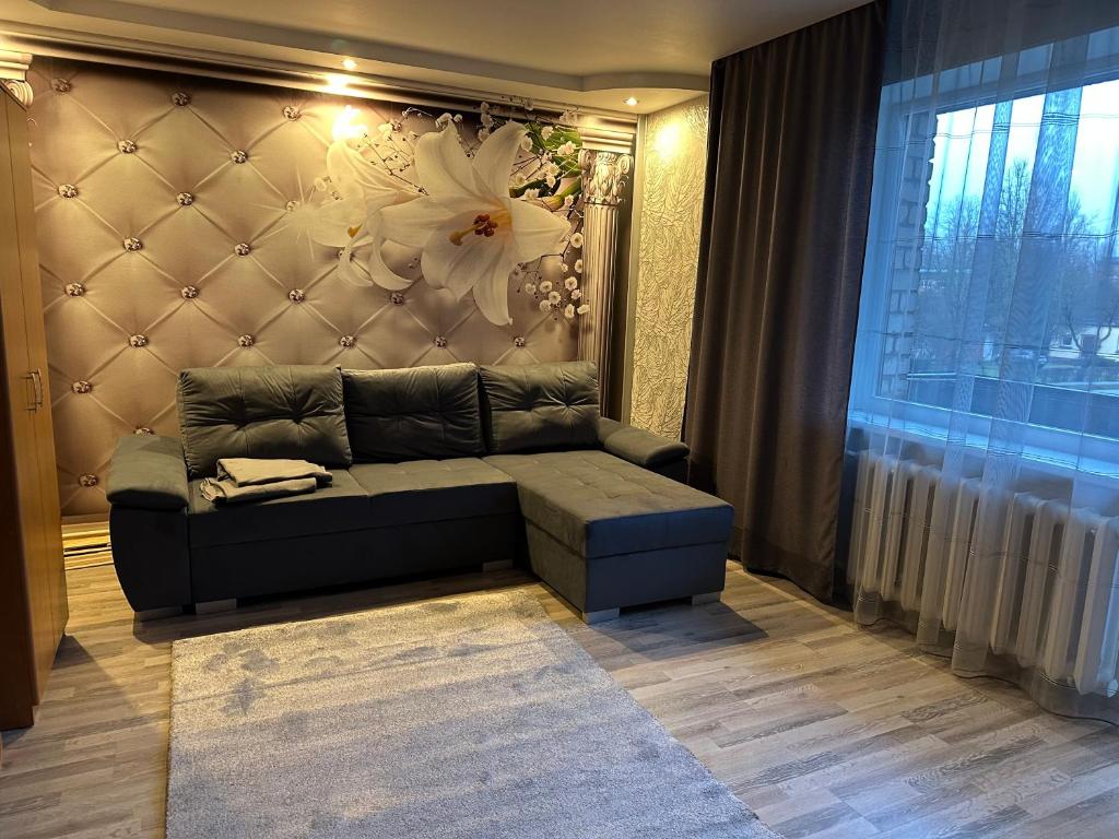 a living room with a couch and a flower on the wall at Rio Apartamenti in Brocēni