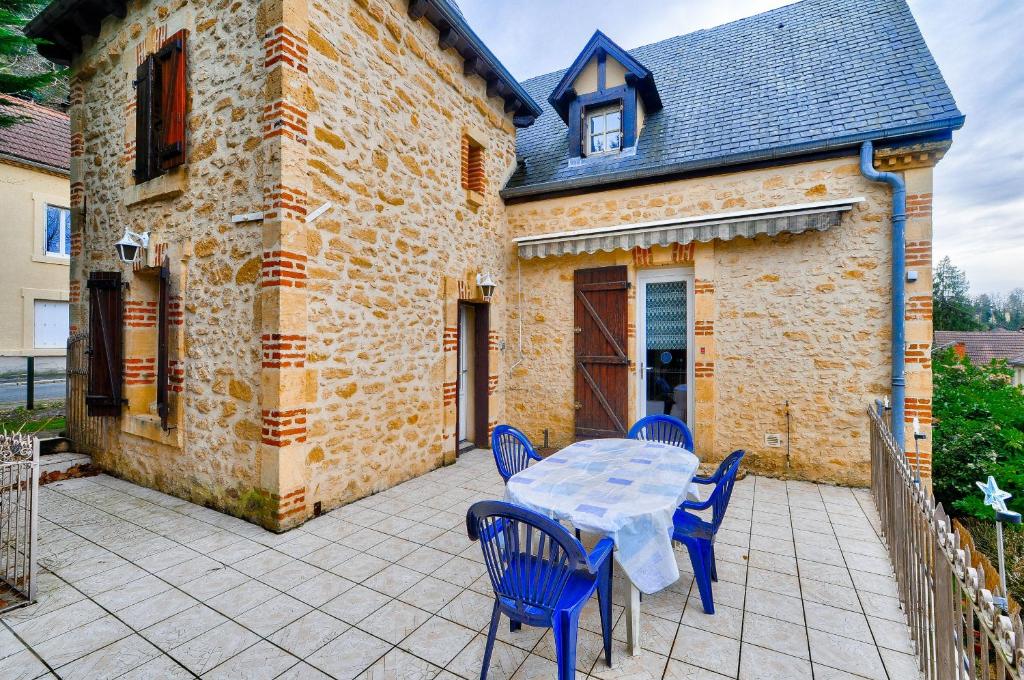 un patio avec une table et des chaises et un bâtiment dans l'établissement Maison en pierre avec une terrasse, ideal pour 4, à Sarlat-la-Canéda