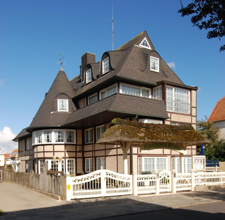 una casa grande con una valla blanca delante de ella en Hotel Appartement Landhaus Stutzi - Hotel Strandperle, en Cuxhaven
