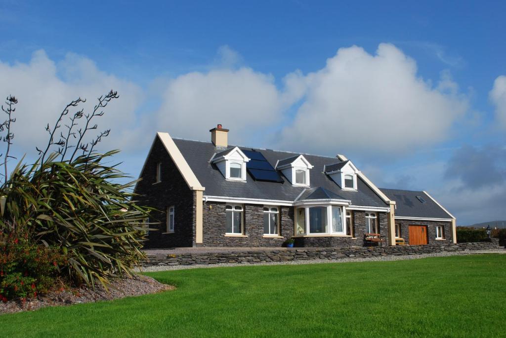 una casa con un césped verde delante de ella en Carraig Liath House en Valentia Island