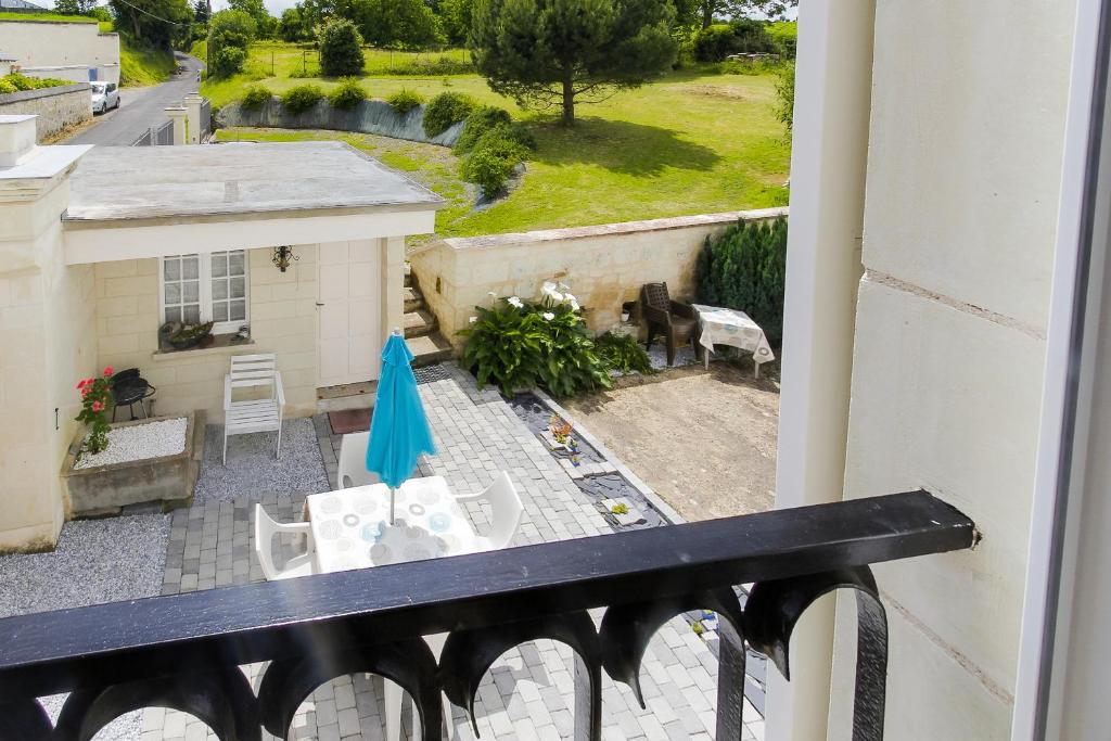 a balcony with a patio with chairs and an umbrella at Les Perdrielles in Fontevraud-l'Abbaye