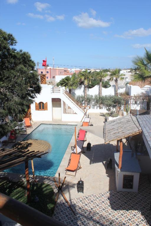 a view of a swimming pool with chairs and trees at La Maison des Vagues in Sidi Kaouki