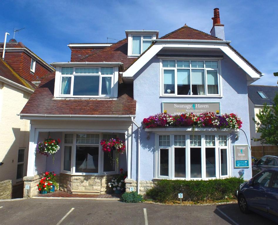 a white house with flower boxes on the front of it at Swanage Haven Boutique Guest House in Swanage