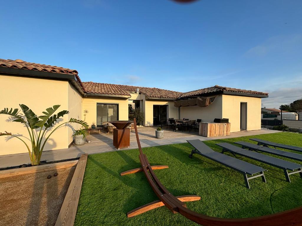 une maison avec une cour dotée d'un hamac dans l'herbe dans l'établissement Chez Marjorie et Nicolas, à Sallèles-dʼAude