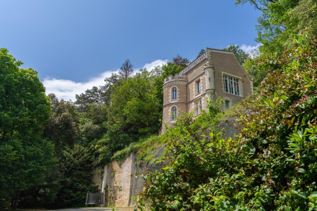 un vieux bâtiment au sommet d'une colline plantée d'arbres dans l'établissement Demeure Historique et Artistique à Amboise avec Piscine, à Nazelles-Négron