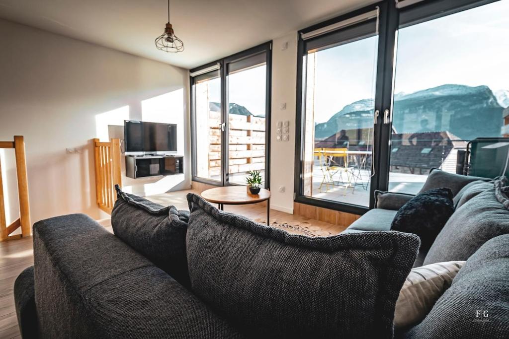 un salon avec un canapé et une grande fenêtre dans l'établissement Le Duplex 80m2, Terrasse privée, Parking, à Thyez