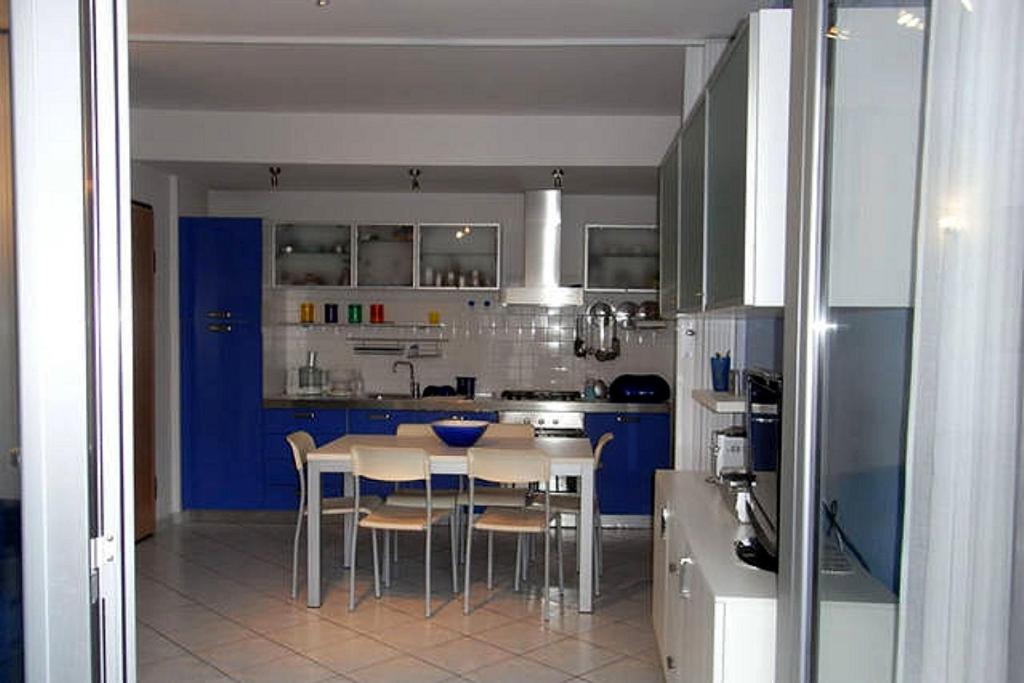 a kitchen with blue cabinets and a table and chairs at Appartamento Blu in Giulianova