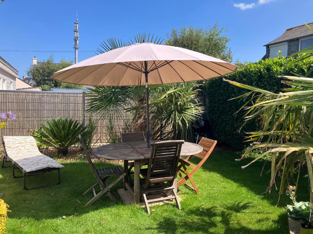 - une table et des chaises sous un parasol dans la cour dans l'établissement Maison avec jardin, terrasse, WIFI au centre de PERROS-GUIREC - Réf 949, à Perros-Guirec