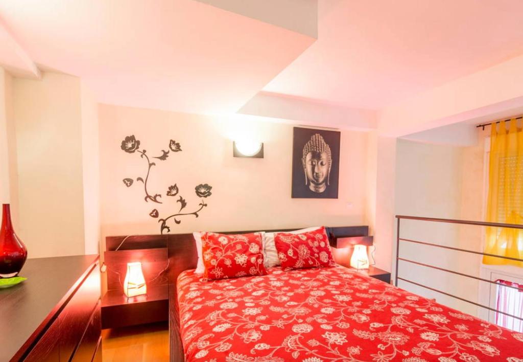 Schlafzimmer mit einem Bett mit einer roten Tagesdecke in der Unterkunft Amazing Apartments Malaga Center in Málaga
