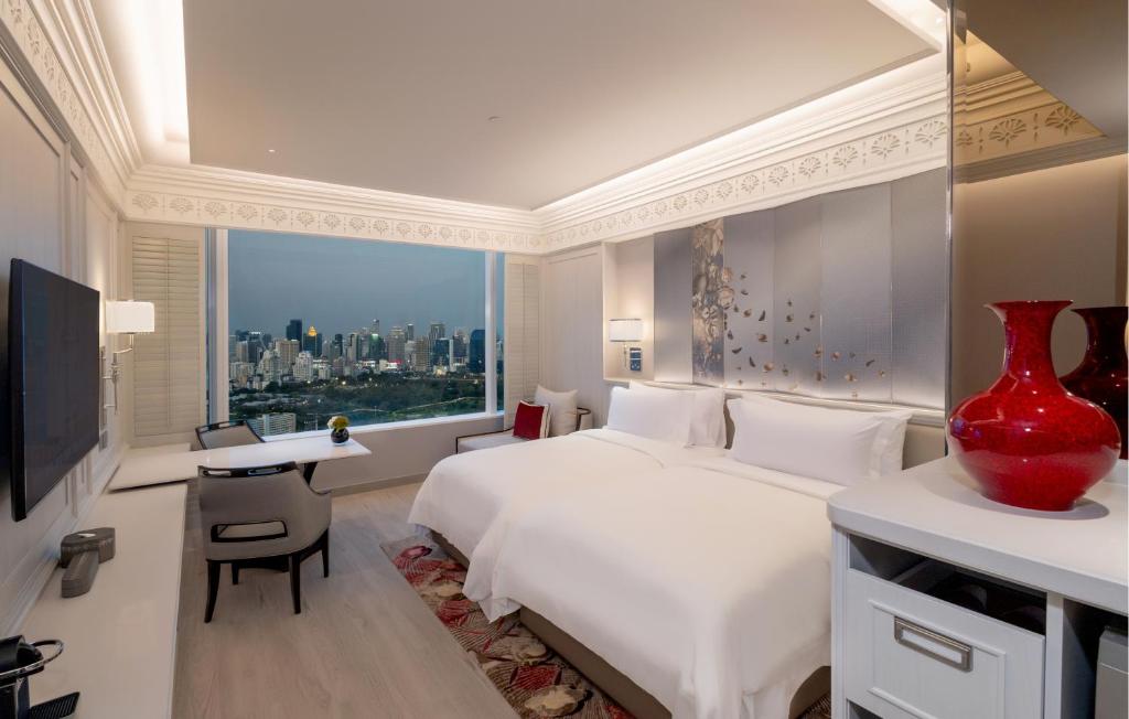 A two-bed room facing a broad Bangkok skyline through a corner window.