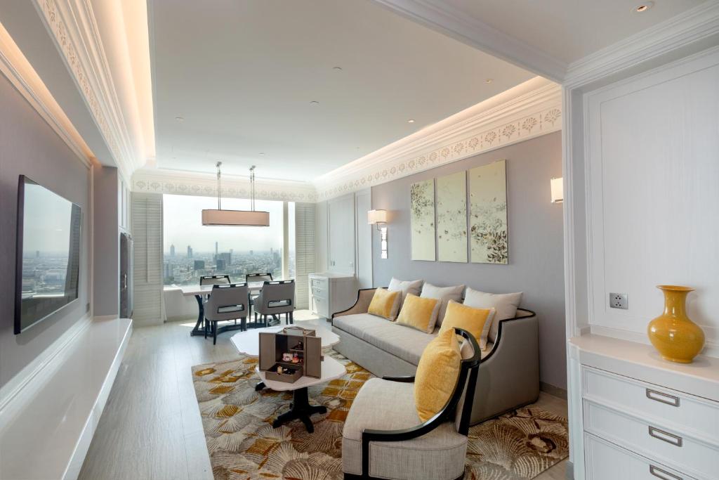 A suite-style living room with a sofa, two lounge chairs, dining table and skyline view.