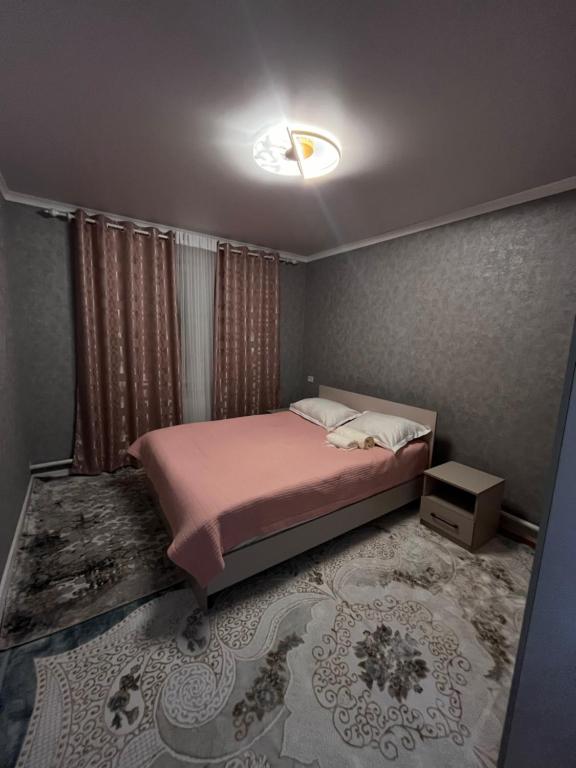 una camera da letto con un letto con un piumone rosa di Private house a Karakol