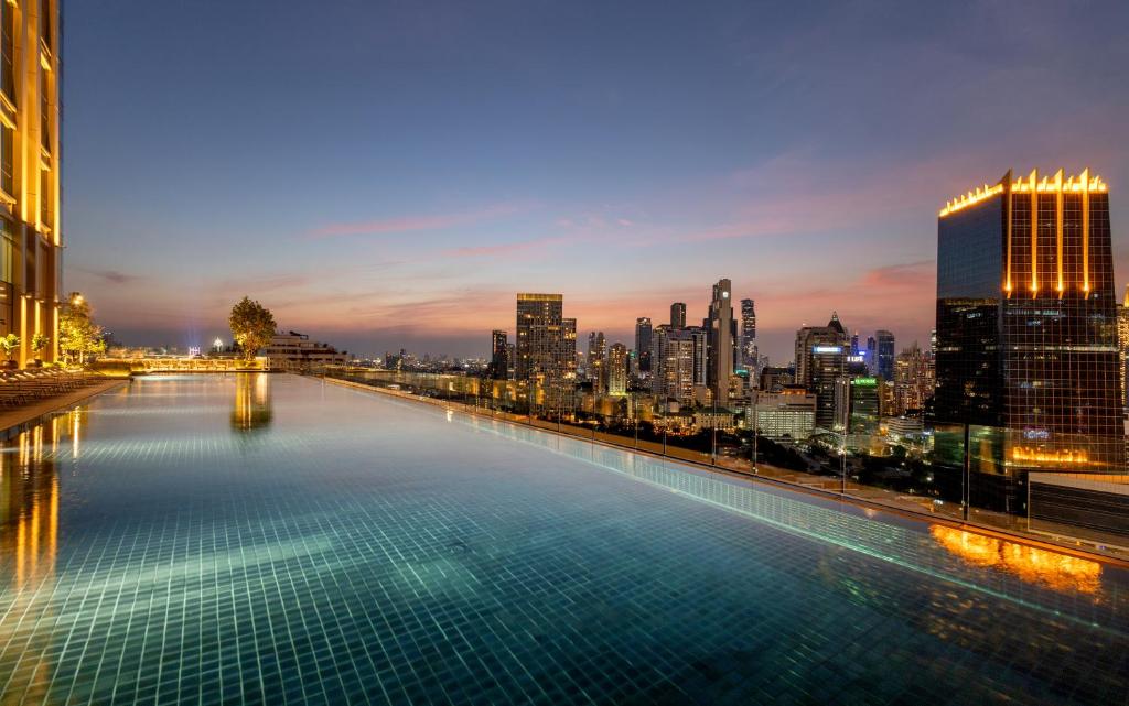 An infinity-edge pool frames Bangkok’s illuminated skyline at dusk.
