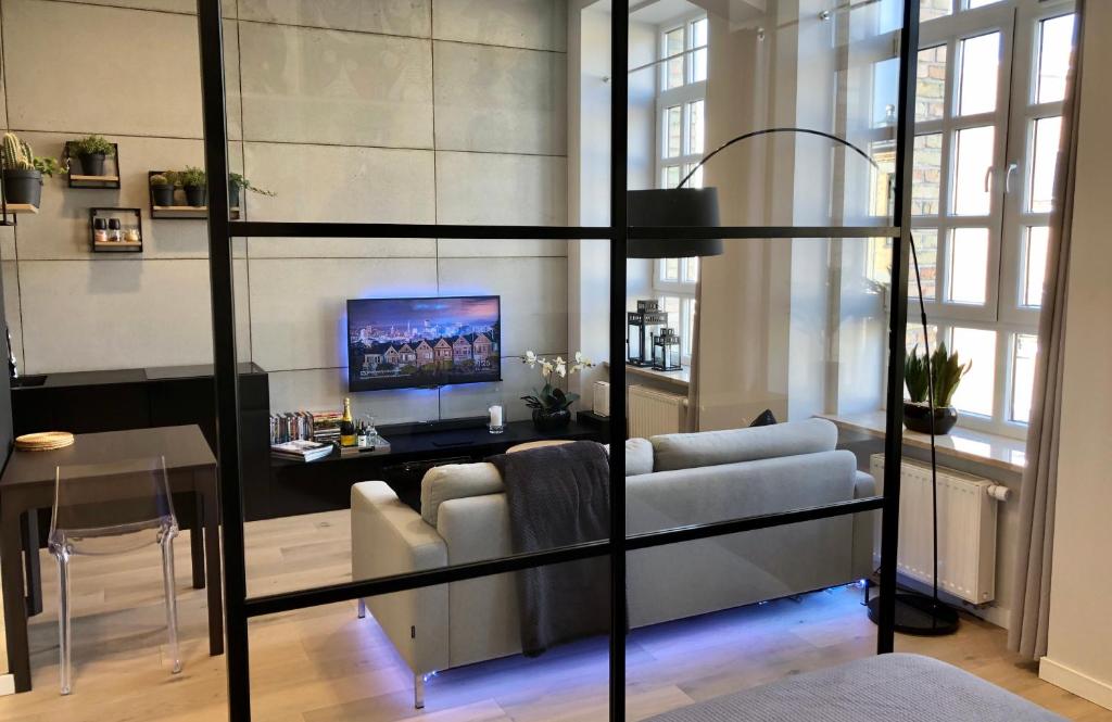 a living room with a couch and a tv at Neon Loft Apartament Bukowskiego in Białystok