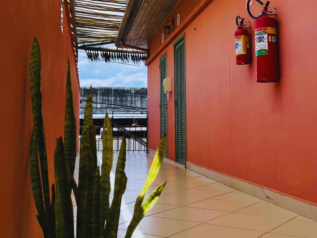 a building with a fire extinguisher on the wall and a plant at Pousada Casa Rosada Ilhabela in Ilhabela
