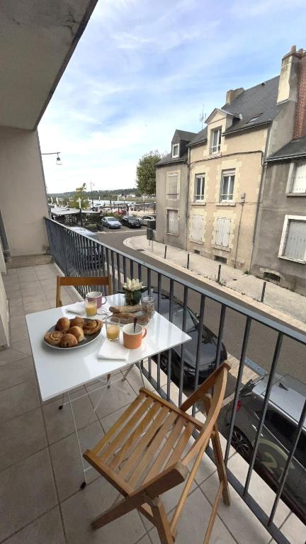 une table avec une assiette de nourriture sur un balcon dans l'établissement Les Rallyes de la Loire - Vue sur Loire - 4 pers, à Blois