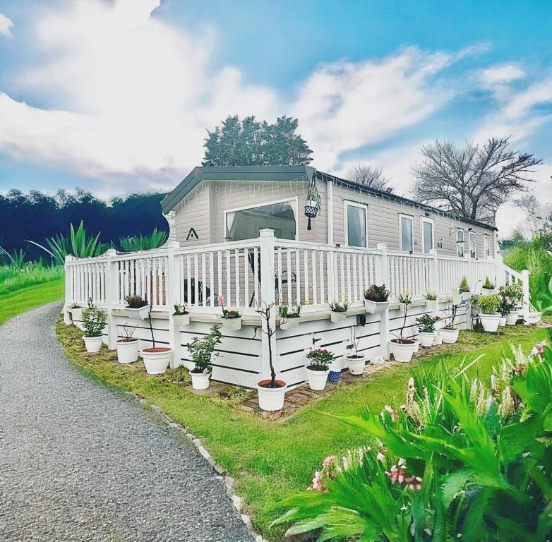 a house with a white fence and potted plants at Caravan by Seaside with Hot Tub in Cornwall countryside in Porth