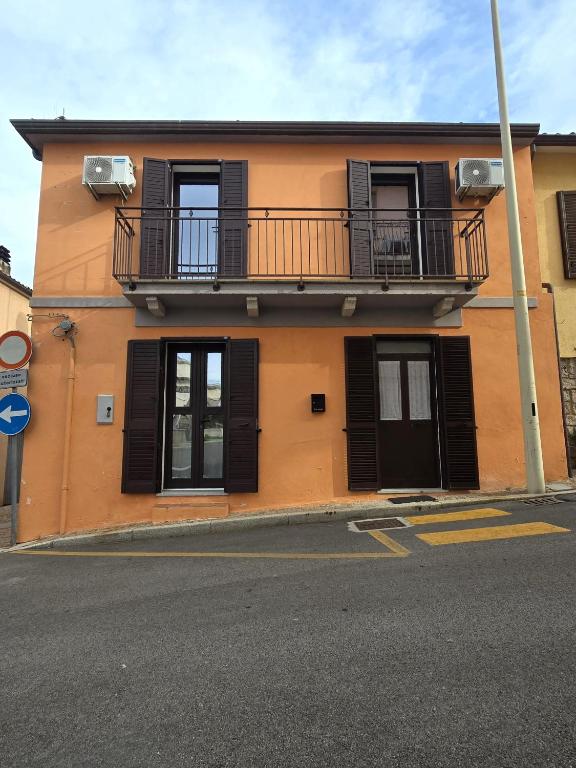an orange building with black shutters and a balcony at Casa rosa in Palau