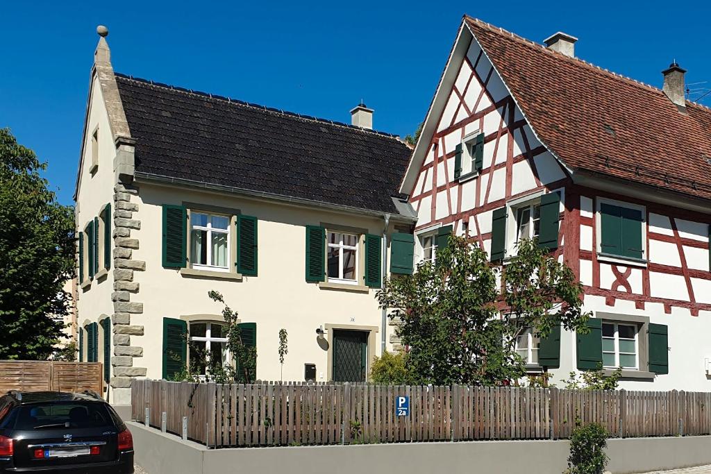 a house with a fence and a car parked in front at Schlößleweg 2a in Bodman-Ludwigshafen