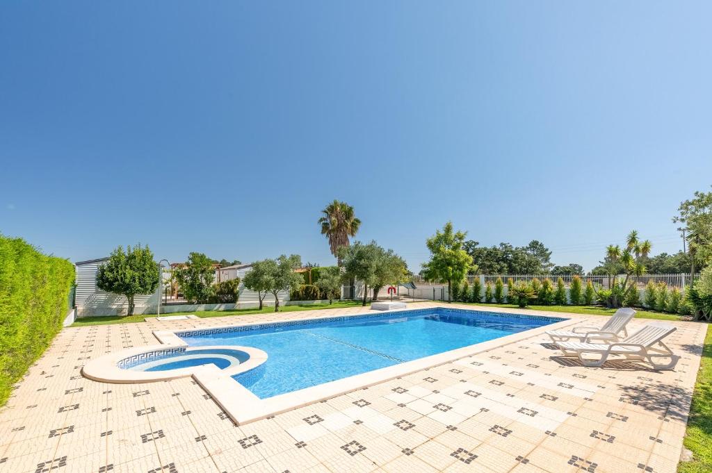 a swimming pool in a yard with two chairs next to it at Magalhães Village by LovelyStay in Santo António da Charneca