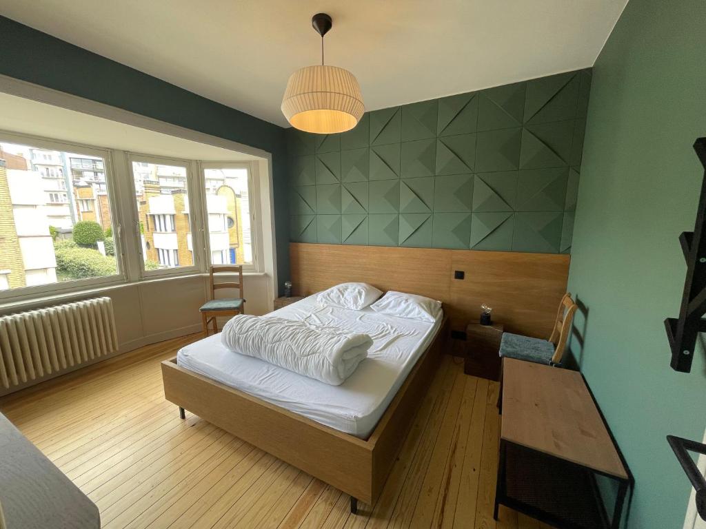a bedroom with a bed and a table and a window at -Le bel abri- à 2 pas de la mer in De Panne
