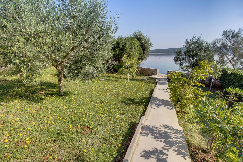 a path through a field with trees and a lake at Apartments Del Sole in Nerezine