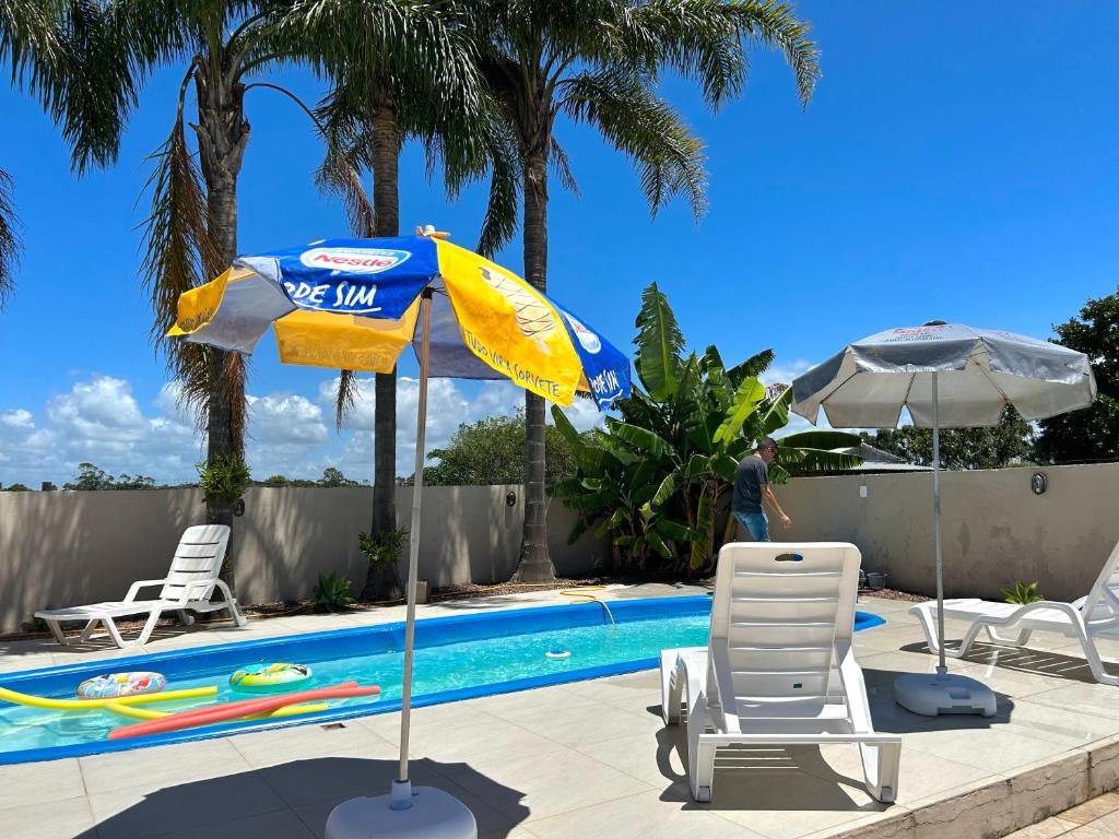 a blue and yellow umbrella and chairs next to a swimming pool at Loft incrível e completo in São Lourenço do Sul
