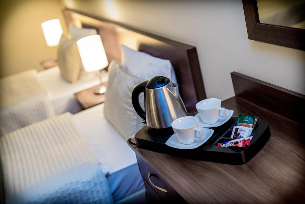 a tray with a tea kettle and cups on a bed at Hotel Kantoria in Tarnów