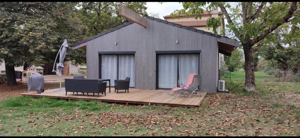 ein Haus mit einer Terrasse mit Stühlen und einem Tisch in der Unterkunft Le Chalet d'Agen in Boé