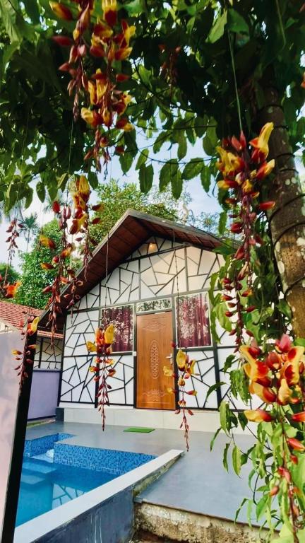 a house with a swimming pool in front of a tree at Josh Holidays Wayanad in Vaduvanchal
