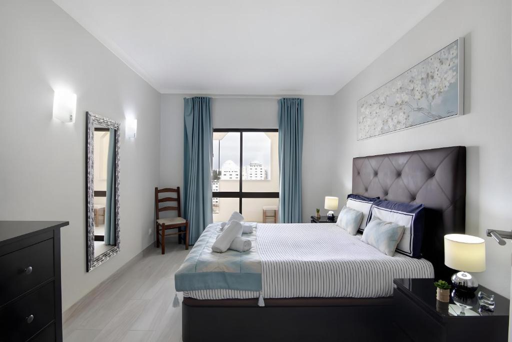 a bedroom with a large bed with blue curtains at Seaside Apartment - Praia da Rocha in Portimão