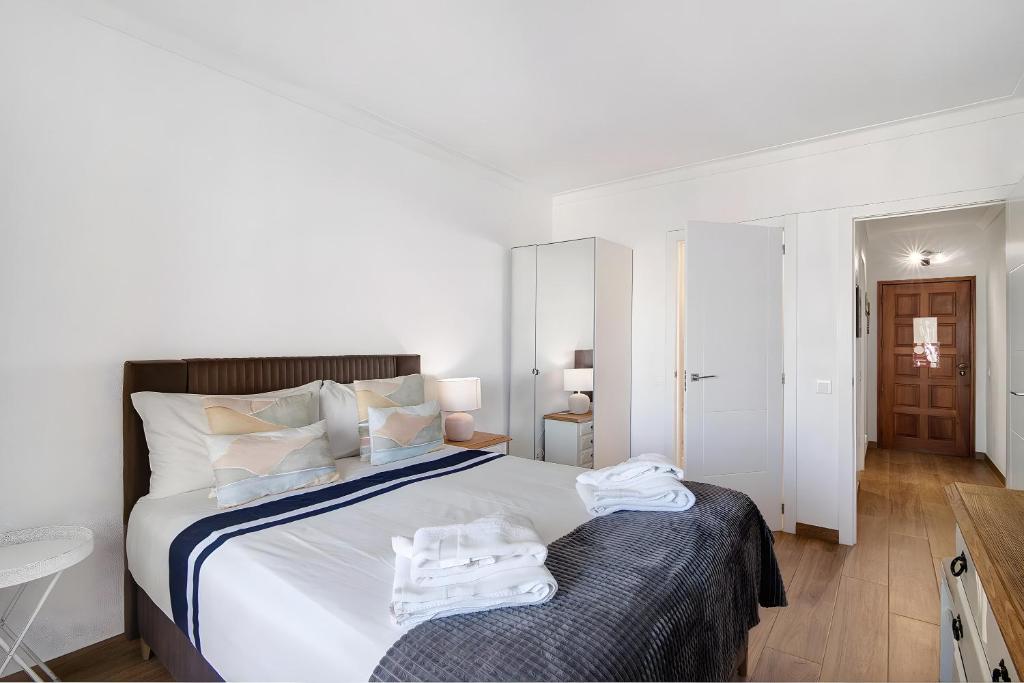 a white bedroom with a large bed with towels on it at Seaside Heaven - Praia da Rocha in Portimão