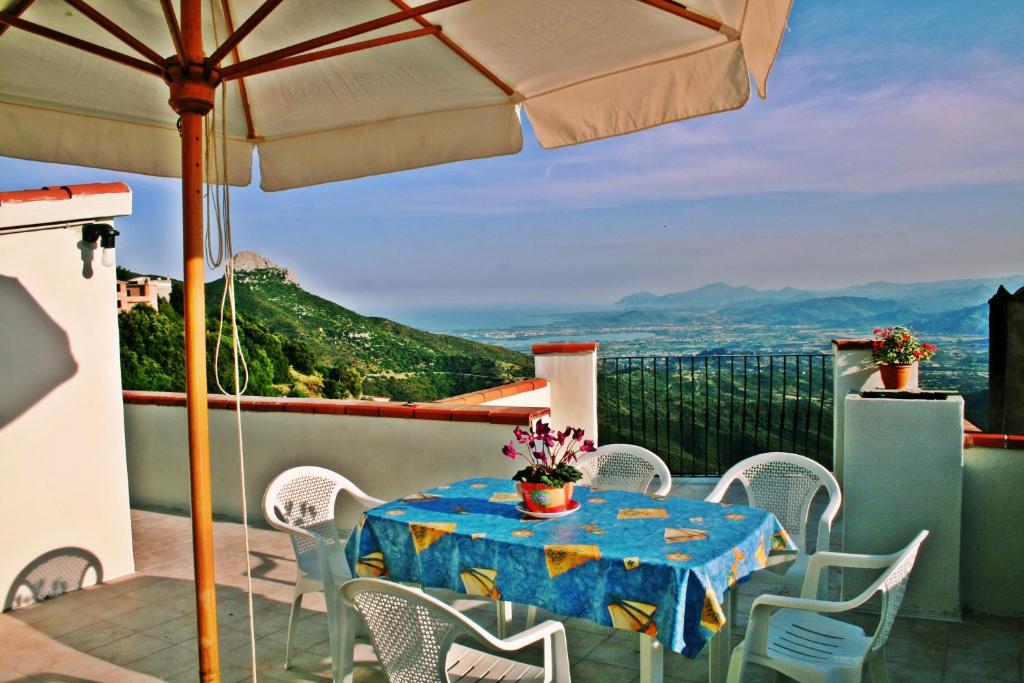 una mesa y sillas en un balcón con sombrilla en Casa Bellavista, en Baunei
