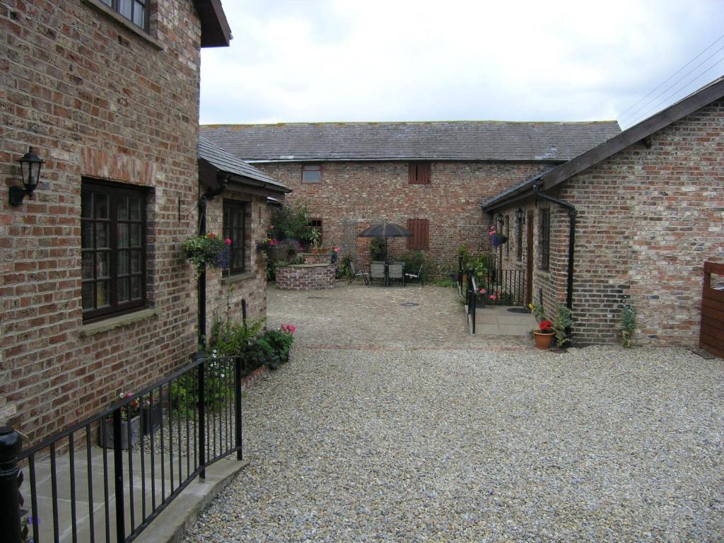 a courtyard of a brick building with a fence at Thompsons Arms Cottages in Flaxton