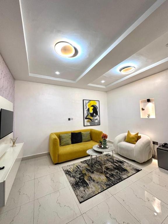 a living room with a yellow couch and a table at Cozy one bedroom apartment in Abuja