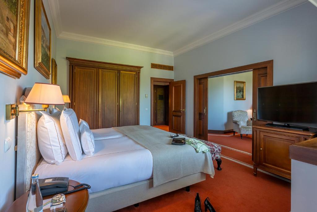 A traditional bedroom pairs a large upholstered bed with dark wood furnishings and a separate sitting area.